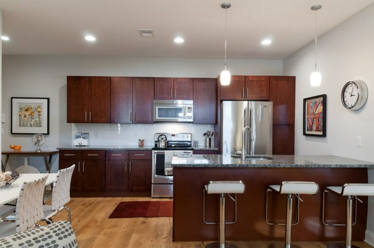 Kitchen with island, hard floors, granite counters, and stainless steel appliances near dining room