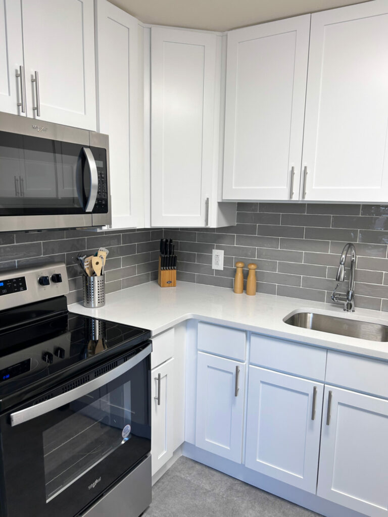 Renovated kitchen with white cabinets and stainless steel appliances.